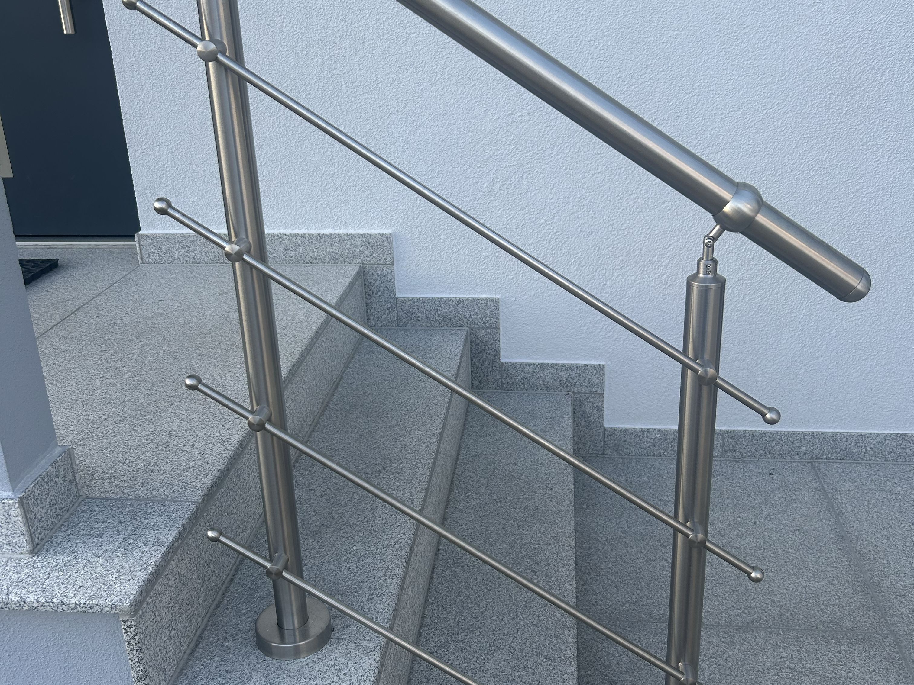 Modernes Edelstahl-Treppengeländer mit Querstäben und Handlauf an Steintreppe