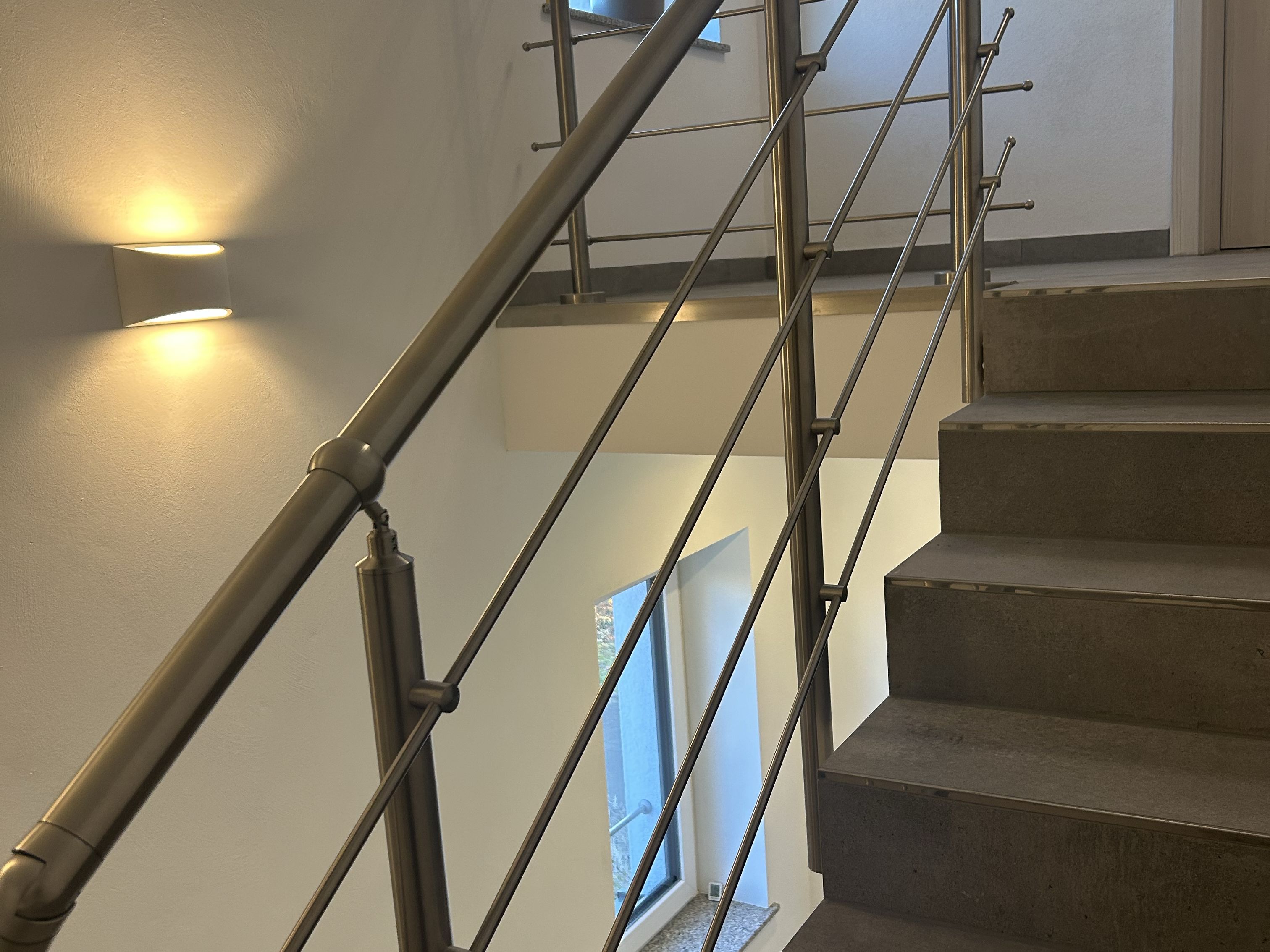 Elegantes Edelstahl-Treppengeländer mit diagonalen Streben im Treppenhaus