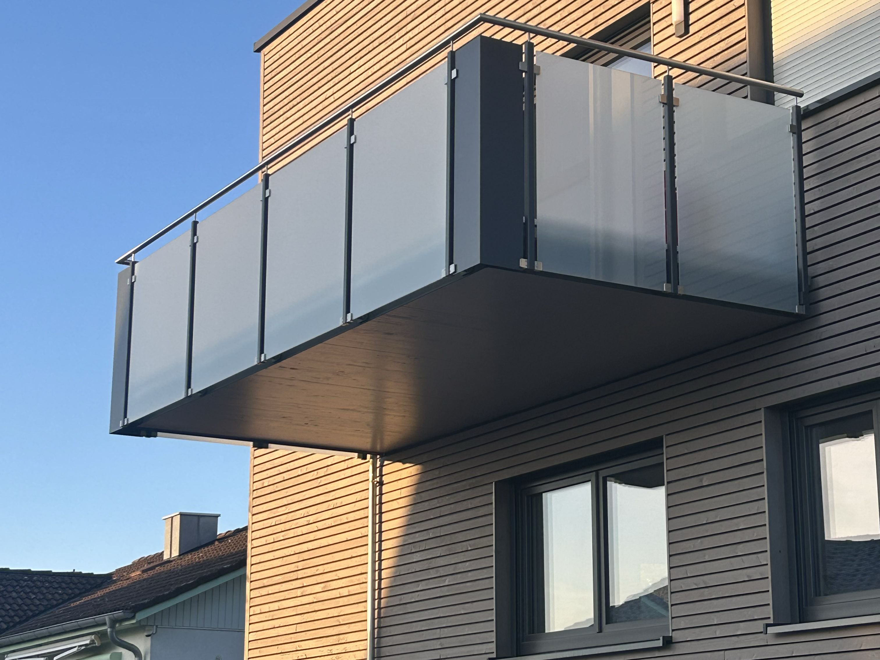 Auskragender Balkon mit Milchglas-Geländer und anthrazitfarbener Metallkonstruktion