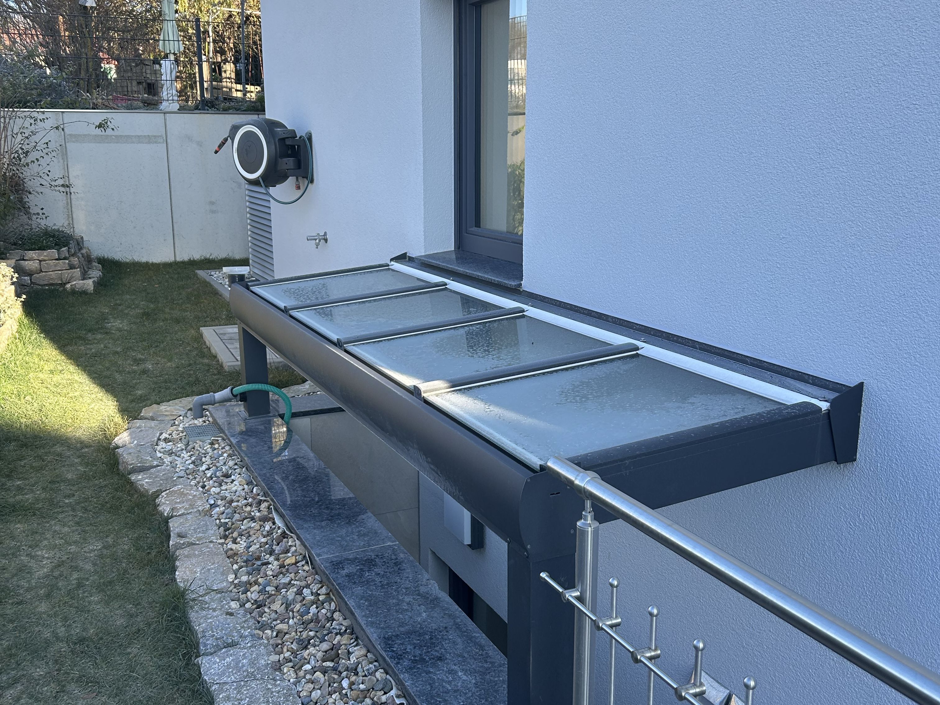 Überdachter Kellerzugang mit Geländer und anthrazitfarbener Metallkonstruktion