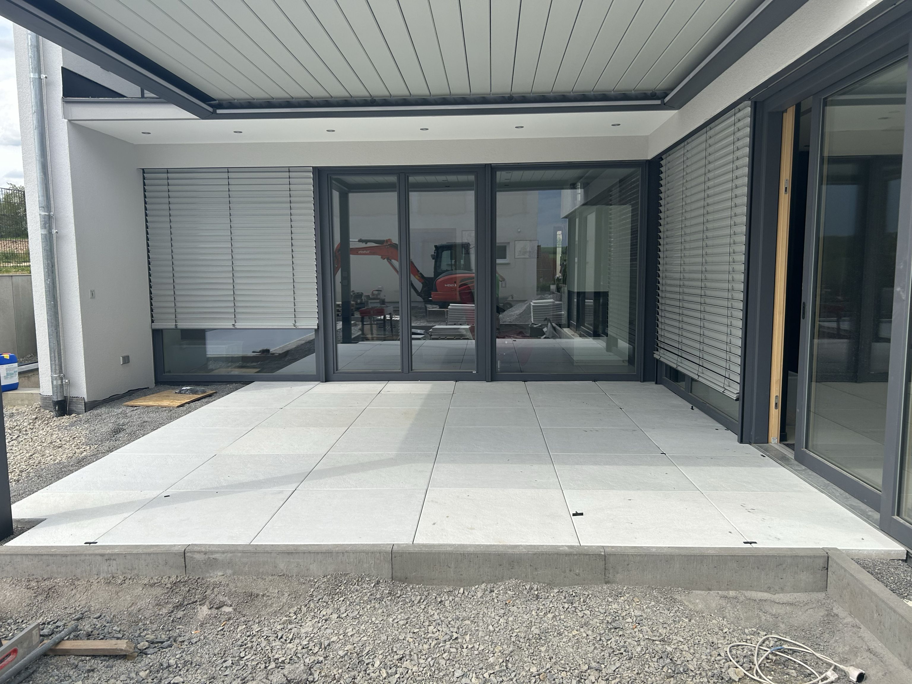 Überdachte Terrasse mit großformatigen Betonplatten und modernen Fenstern