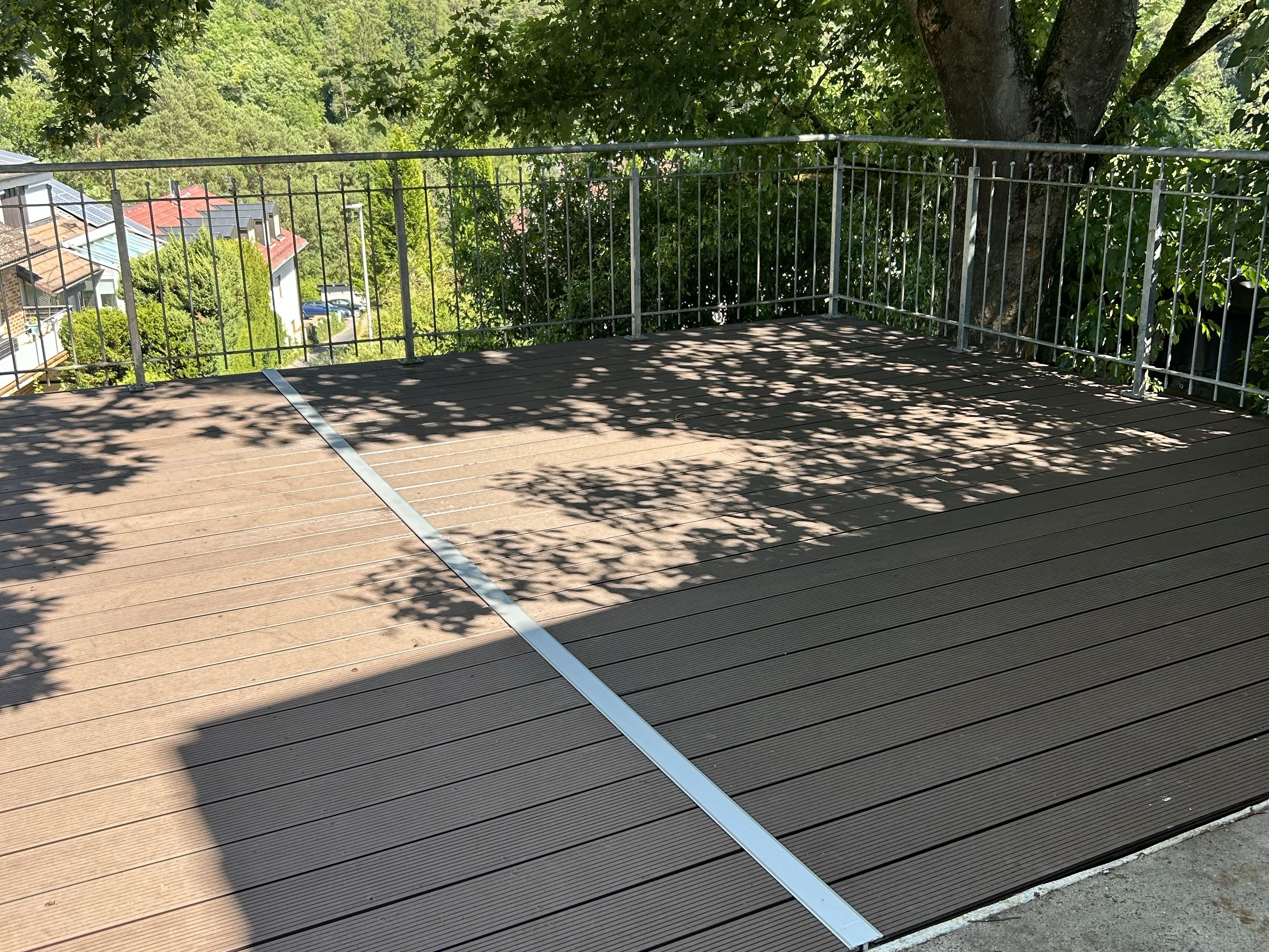 Große WPC-Terrasse mit Metallgeländer und Blick in den Garten