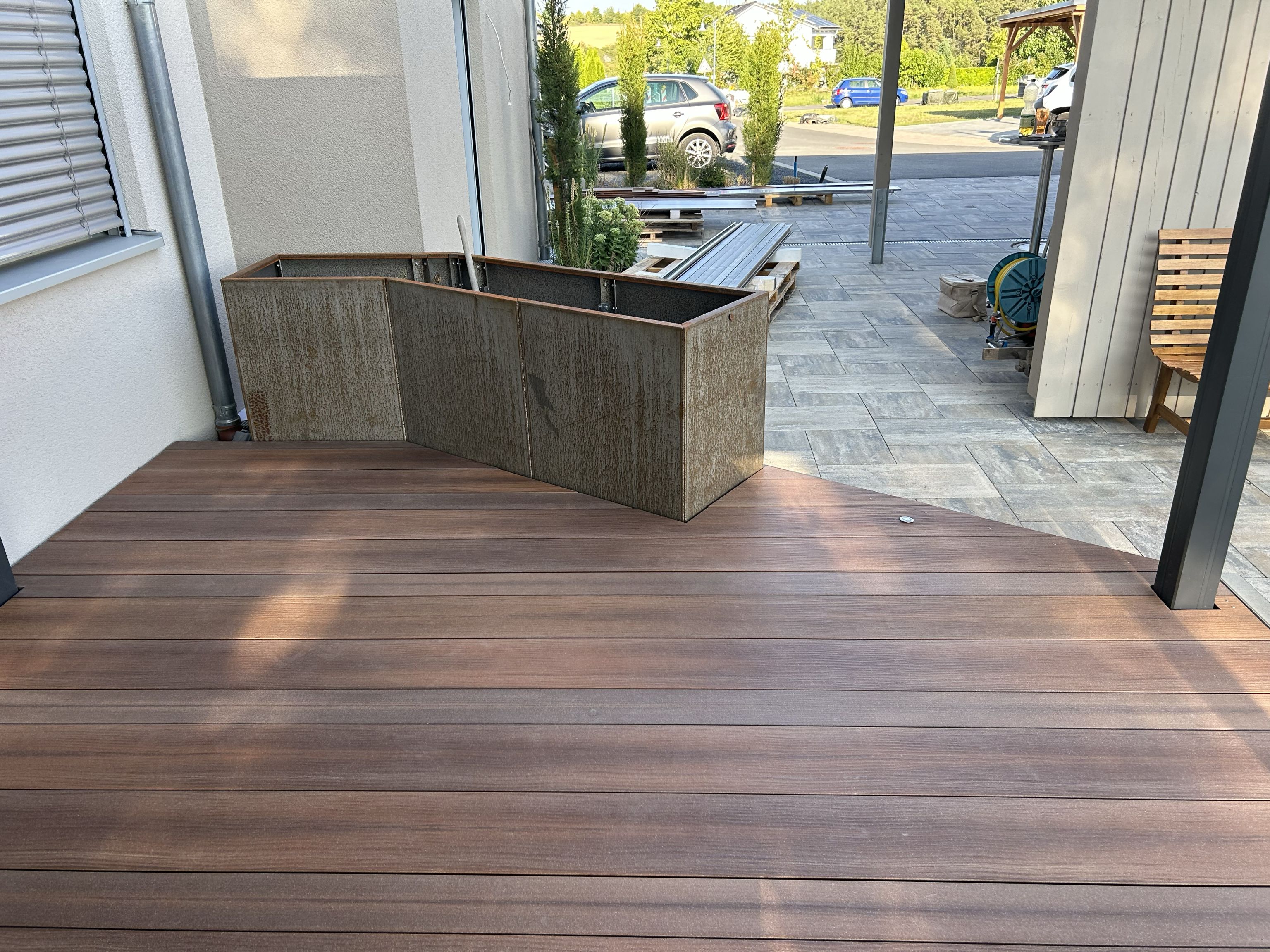 WPC-Terrasse mit Hochbeet und Übergang zu Steinplatten