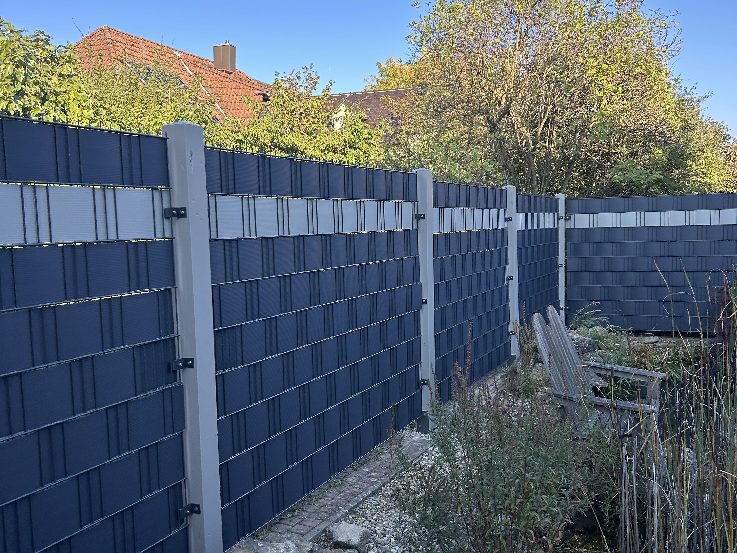 Moderner Sichtschutzzaun mit eingeflochtenen Lamellen am Teich